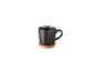 Eine schwarze Kaffeetasse auf einem Holzuntersetzer.