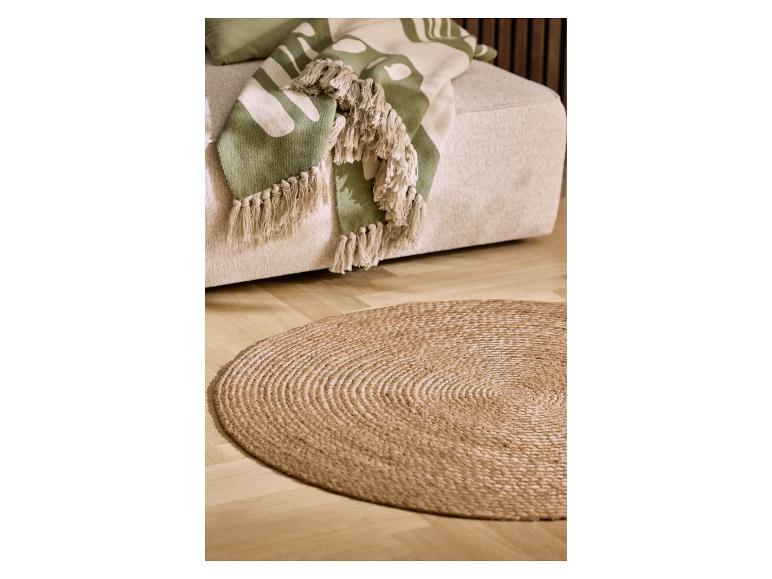 Beiges Sofa mit grüner Blätterdecke und rundem Jute-Teppich auf Holzboden.