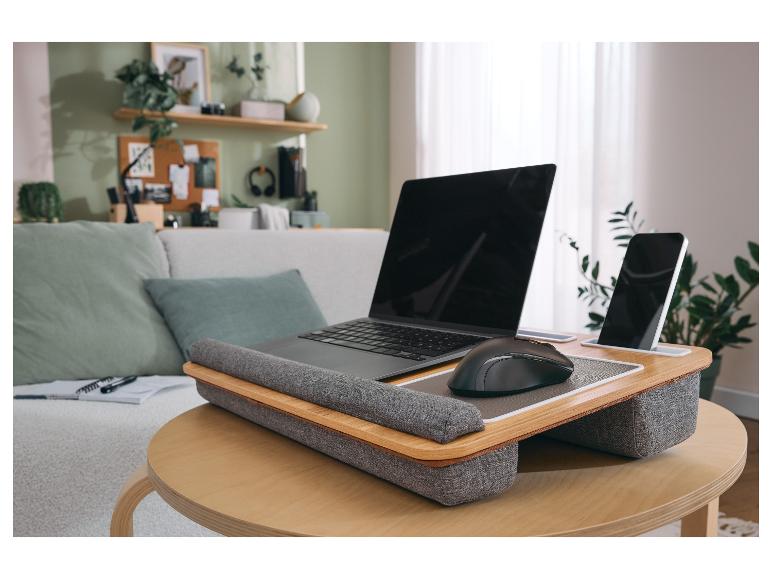 Laptop und Smartphone auf einem hölzernen Lapdesk auf einem Couchtisch im Wohnzimmer.