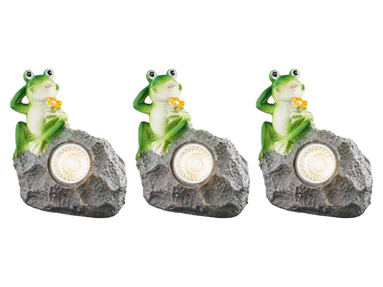 Drei solarbetriebene Froschlampen auf Felsen.
