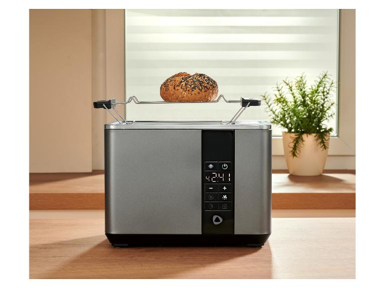 Silberner Toaster mit Digitalanzeige und Brötchen auf dem Aufwärmrost.