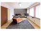 Wohnzimmer mit orangefarbener Chaiselongue, grauem Teppich und Kamin.