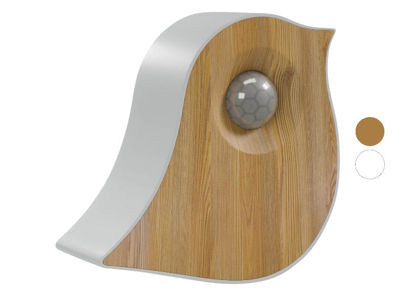 Wanddekoration in Vogelform aus hellem Holz mit grauem Rand und einer grauen Kugel in der Mitte.