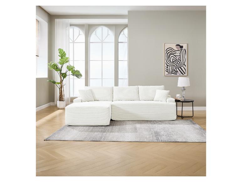 Weißes Modulsofa mit Kissen, grauem Teppich und Pflanze in einem hellen Wohnzimmer.