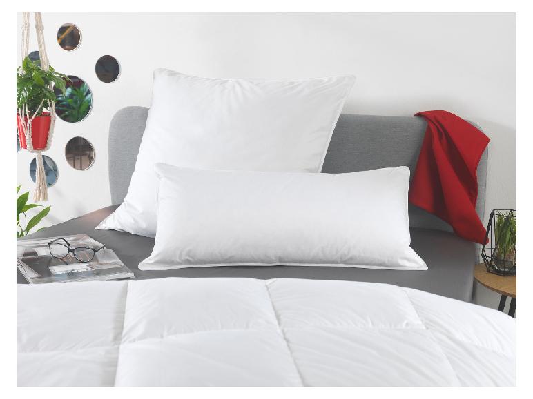 Bett mit weißen Kissen, Bettdecke und roter Decke, mit Pflanzen und dekorativen Spiegeln.