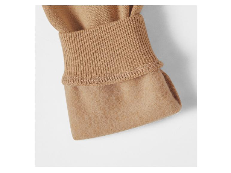 Detail des Innenfutters eines beigefarbenen Hoodies mit geripptem Bündchen.