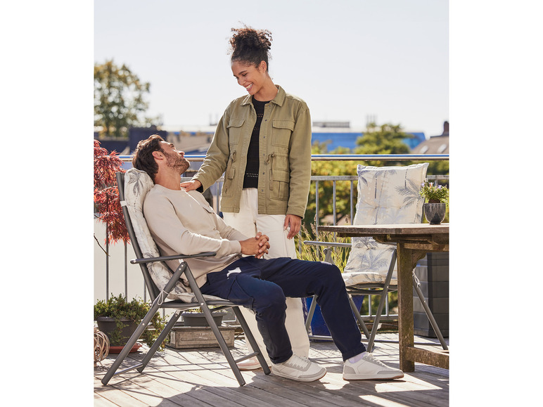 Zwei Personen sitzen auf einem Balkon auf einem Stuhl mit einem tropischen Kissen.