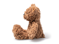 Weicher brauner Teddybär im Profil sitzend auf weißem Hintergrund.