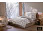 Bettwäsche-Set mit Wintermuster auf einem Bett in einem gemütlichen Schlafzimmer mit Schneeblick.