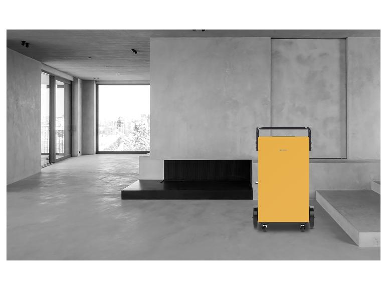 Ein gelber tragbarer Luftentfeuchter in einem modernen, minimalistischen Raum.