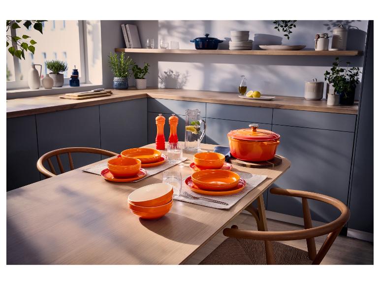 Orangenes Steinzeug-Geschirr von SILVERCREST® auf einem hölzernen Esstisch.