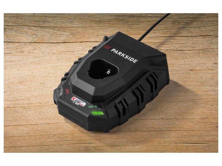 Schwarzes Akkuladegerät auf einem Holztisch, mit grüner LED-Anzeige.