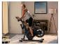 Frau trainiert auf einem Heimtrainer in einem modernen Wohnzimmer.