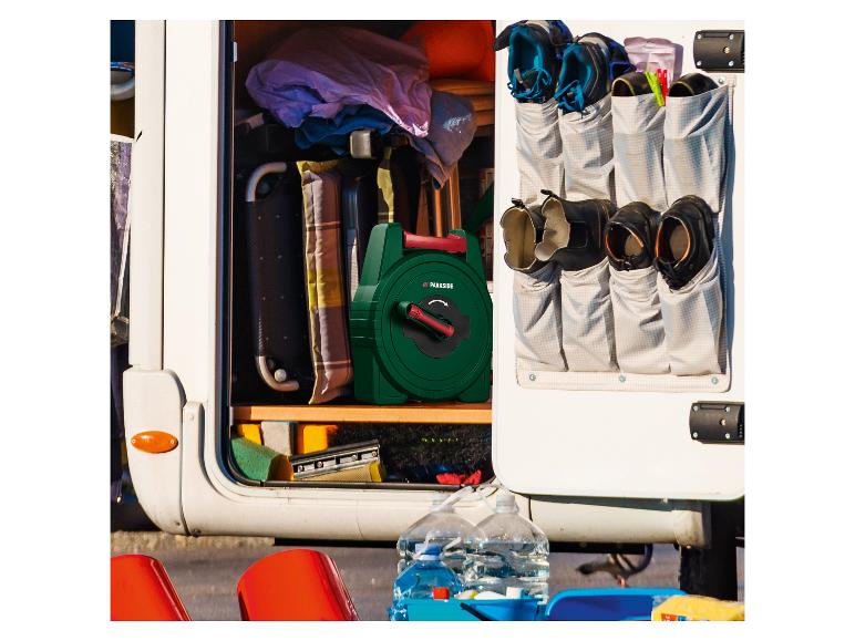 Offener Wohnmobil-Stauraum mit grünem Schlauchaufroller, Schuhen in Hängeorganizer und Reinigungsutensilien.