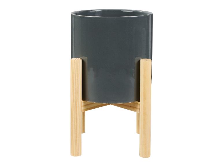Ein grauer Blumentopf auf einem Holzständer.