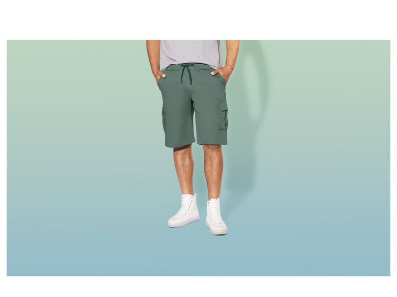 Mann trägt grüne Cargo-Shorts und weiße Turnschuhe.