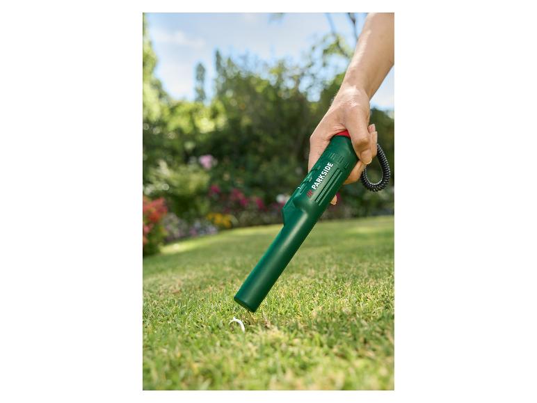 Hand-Metalldetektor sucht nach einem Ring im Gras.