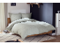 Hellgrüne Bettwäsche mit Blattmuster auf einem Holzbett in einem modernen Schlafzimmer.