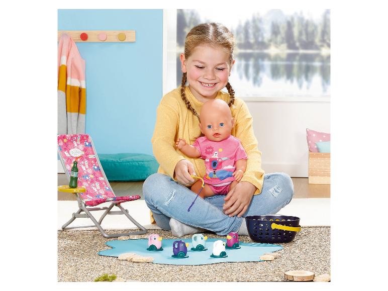 Mädchen spielt mit einer Puppe und einem Angelspiel mit bunten Pinguinen.