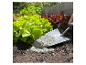 Gartenschaufel mit pulverförmigem Dünger neben grünem Salat im Beet.