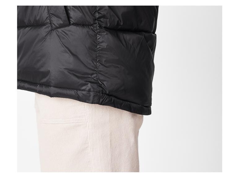 Schwarze Daunenjacke über Cordhose.