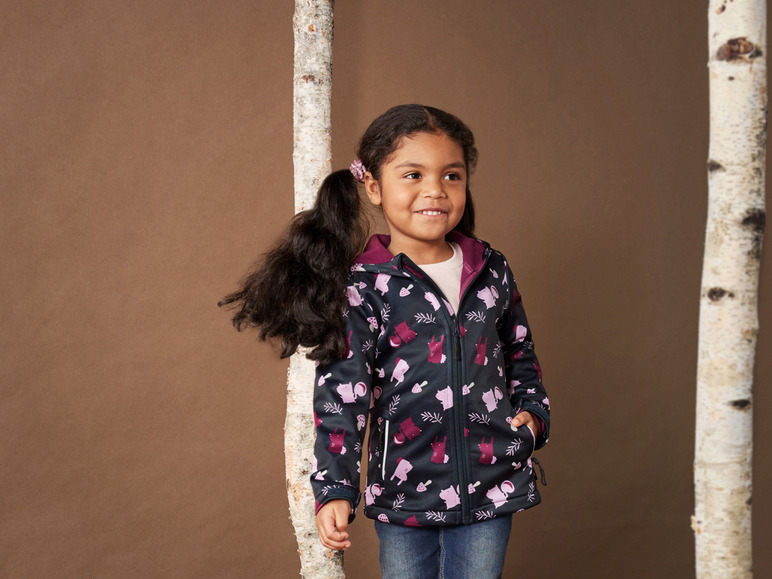 Ein Mädchen trägt eine schwarze Jacke mit einem Tier- und Pilzprint.