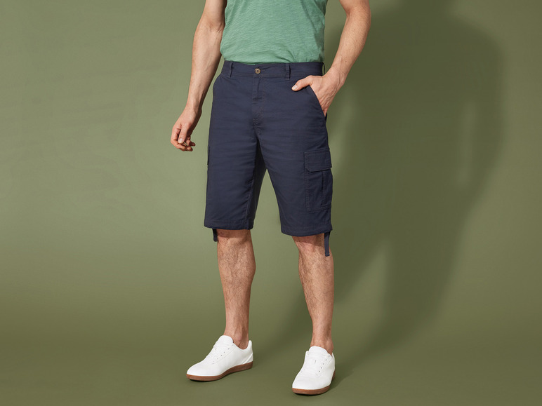 Ein Mann trägt blaue Cargo-Shorts und weiße Sneaker.
