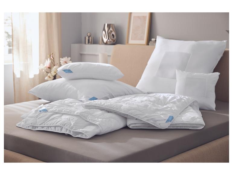 Weiße Kissen und Decken auf einem Bett, mit blauen Hydrocool-Etiketten.