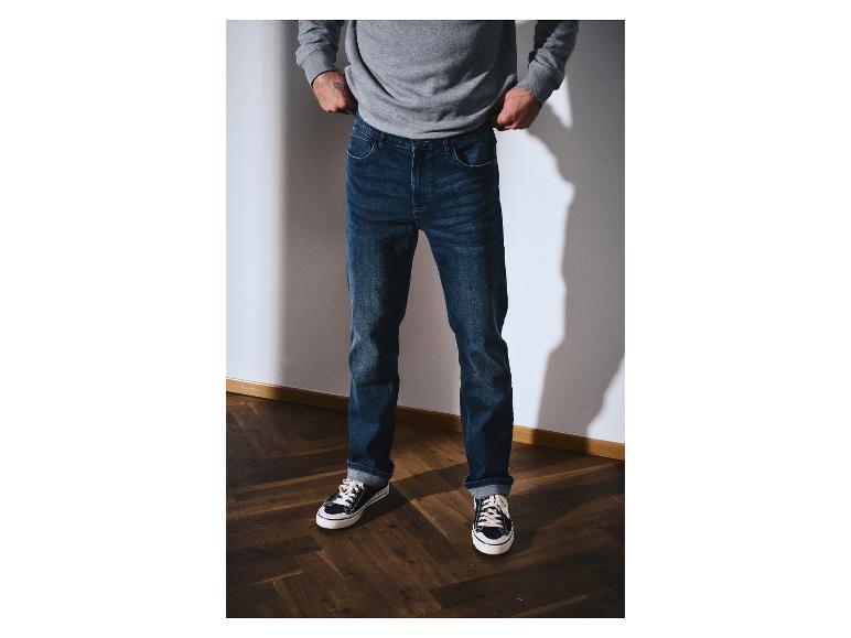 Mann in grauem Sweatshirt und dunkelblauer Jeans mit Turnschuhen.