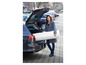 Eine Frau lädt eine Matratze in den Kofferraum eines Autos.