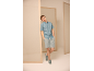 Mann in hellblauem Kurzarmhemd, grauen Shorts und Sneakern.