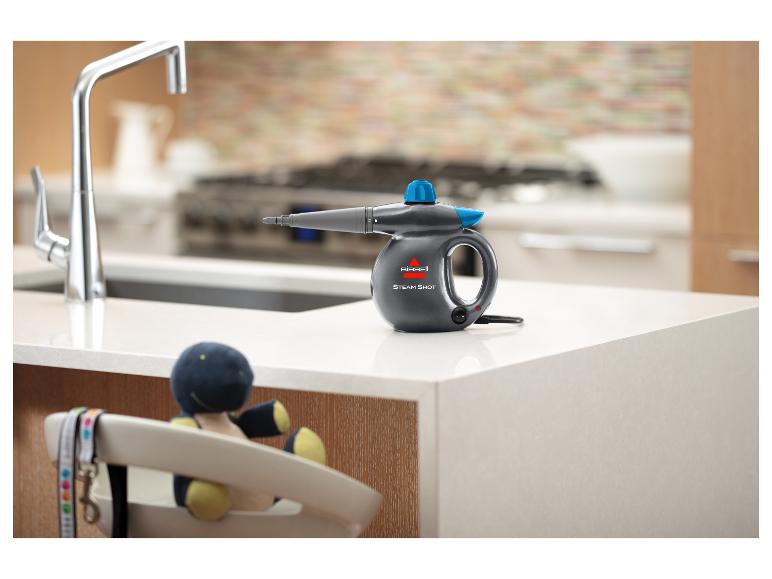 Bissell Steam Shot Dampfreiniger auf einer Küchenarbeitsplatte mit Wasserhahn und Spielzeug im Hintergrund.