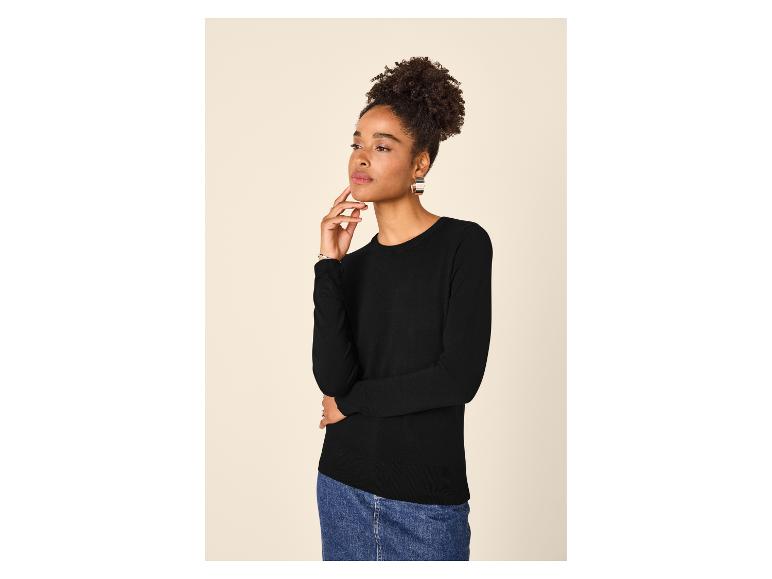 Frau in schwarzem Pullover und Jeansrock, blickt zur Seite.