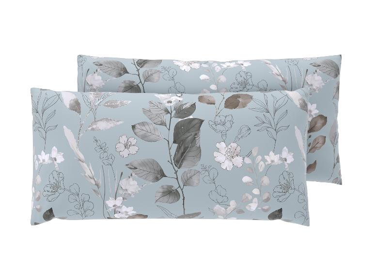 Zwei Kissen mit Blumenmuster in Grautönen auf blauem Hintergrund.