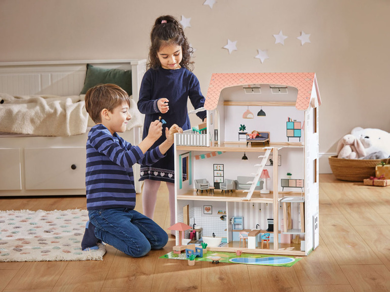 Zwei Kinder spielen mit einem mehrstöckigen Holzpuppenhaus.