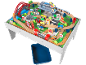Holzeisenbahn-Set auf Spieltisch mit Brücke, Bahnhof, Fahrzeugen und Figuren.