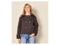 Blonde Frau in einer dunkelbraunen zweireihigen Jacke und blauen Jeans.