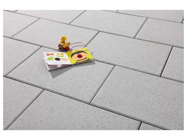 Graue Terrassenplatten mit Kinderbuch und Holzspielzeug.
