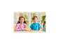 Zwei Kinder spielen mit einem Spielzeug-Imbisswagen und Miniatur-Tierfiguren auf einem weißen Tisch.
