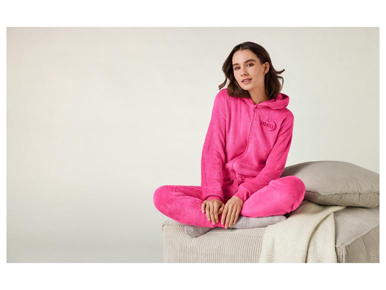 Eine Frau trägt einen rosafarbenen Schlafanzug mit Kapuze und dem Schriftzug 'Dreams'