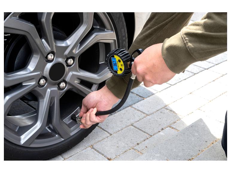 Mann prüft Autoreifendruck mit einem digitalen Messgerät.