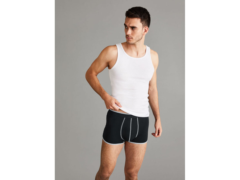 Mann in einem weißen Tanktop und schwarzen Boxershorts.