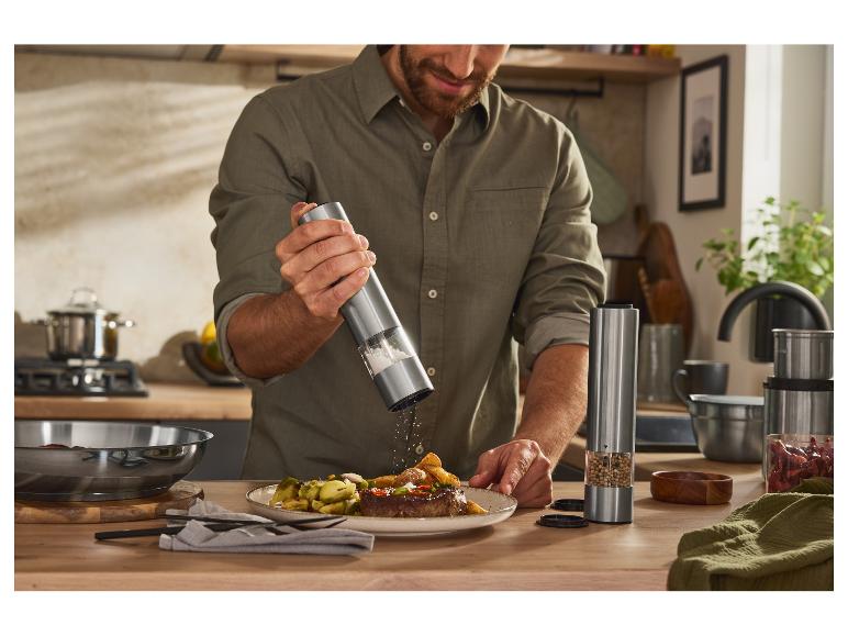 Mann würzt Steak mit elektrischer Salz- und Pfeffermühle.