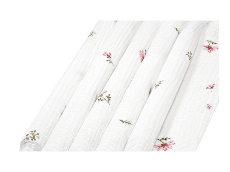 Weißer Stoff mit rosa und grünem Blumenmuster, gefaltet.