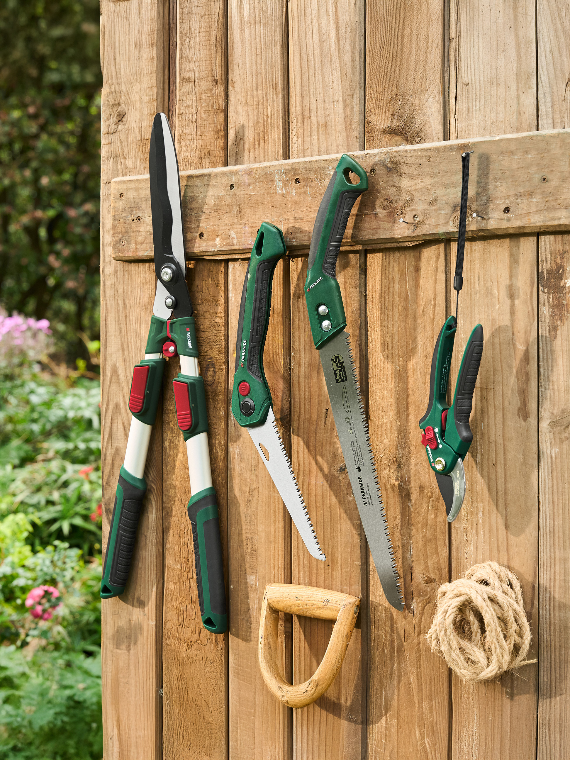 PARKSIDE Gartenscheren, Sägen und Astscheren hängen an einem Holzzaun.