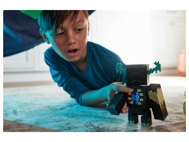 Junge spielt mit einer Minecraft Warden Actionfigur auf einem Teppich.