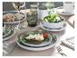 Gedeckter Tisch mit Keramiktellern, Gläsern und Gerichten mit Salat und Käse.
