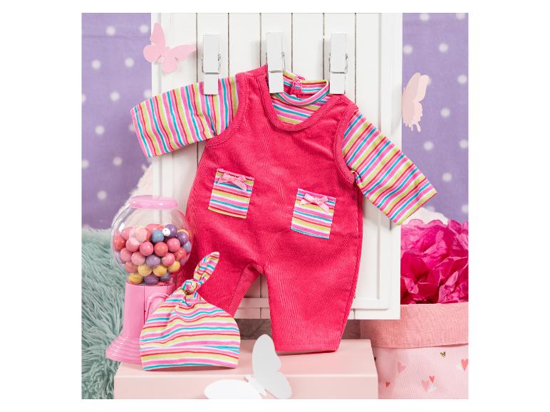 Rosa gestreifte Babykleidung und ein Süßigkeitenautomat auf lila Hintergrund.