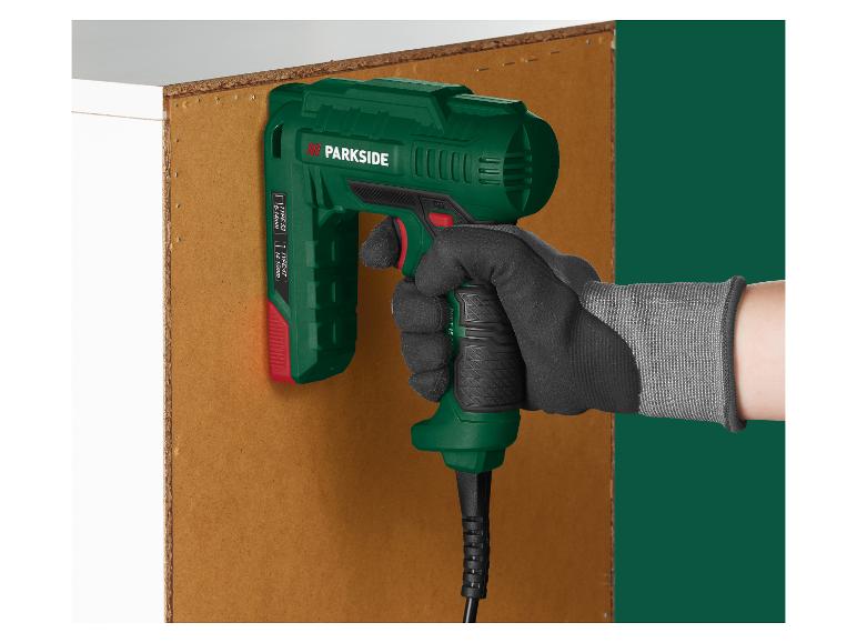 Eine Hand hält eine elektrische Tackerpistole an eine Holzplatte.