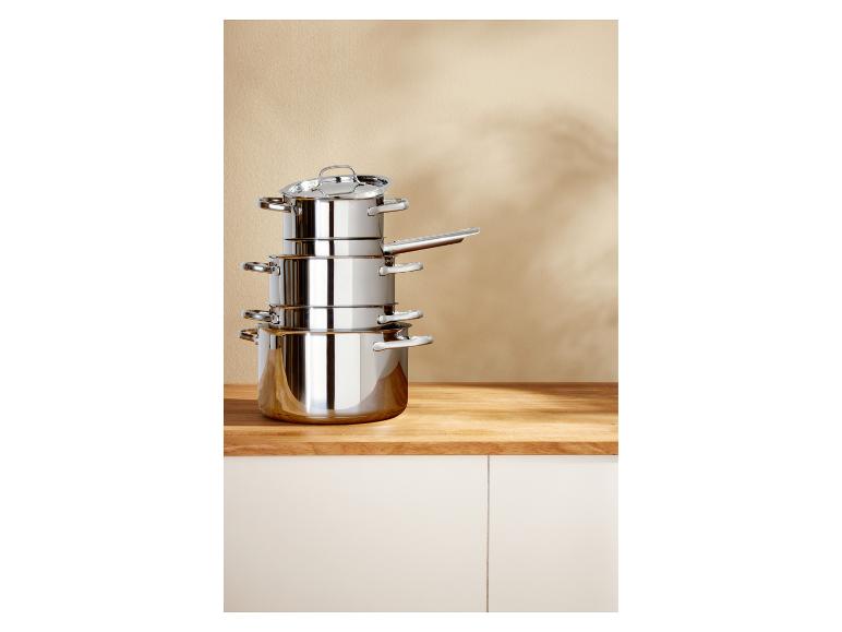Set aus Edelstahl-Töpfen und -Pfannen, gestapelt auf einer Holztheke.